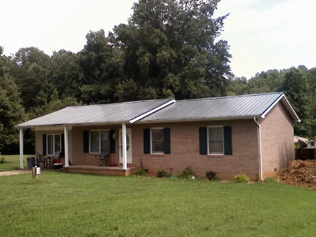Gray metal roof on a brick ranch house with a side carport in Gadsden