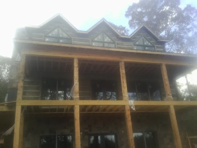 Dormers and porch framing on a large log home under construction — Roof Coating work by our crew in Gadsden